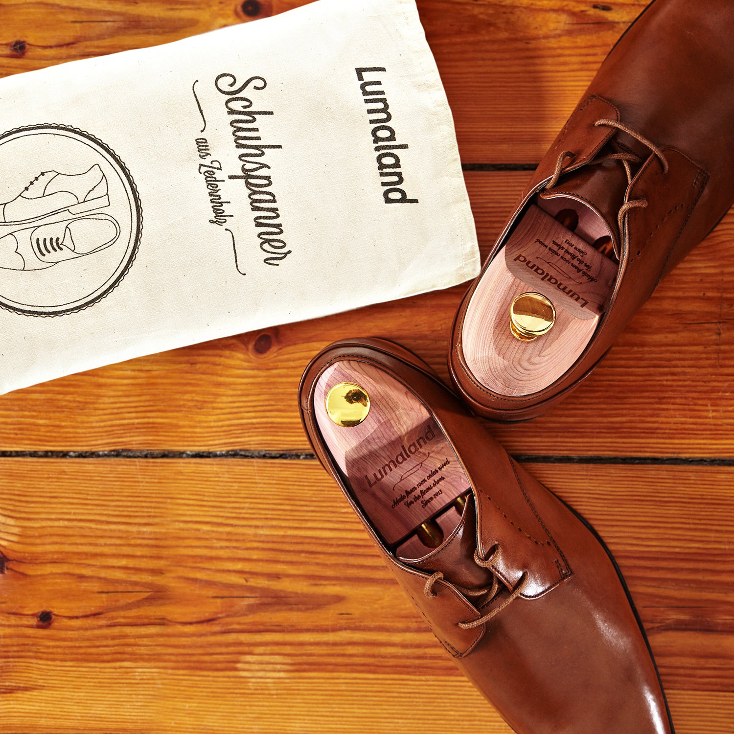 Schuhspanner unisex - Zedernholz - Größe 44/45 in Lederschuhen mit Baumwollbeutel auf Holzboden liegend.