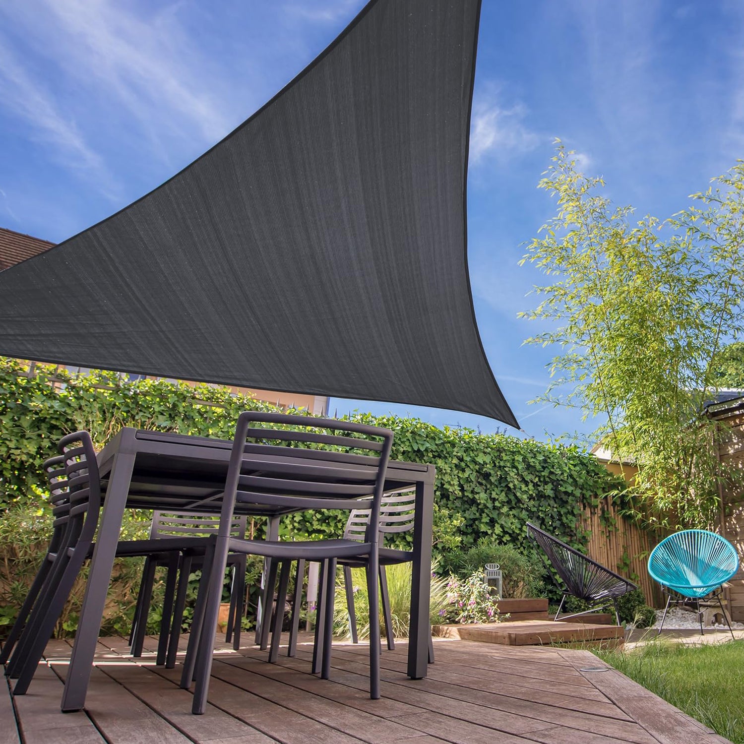 Sonnensegel 100% HDPE - Dreieck 3 x 3 Meter - dunkelgrau als stabiler UV-Schutz über Terrasse mit Gartenmöbeln und Pflanzen.