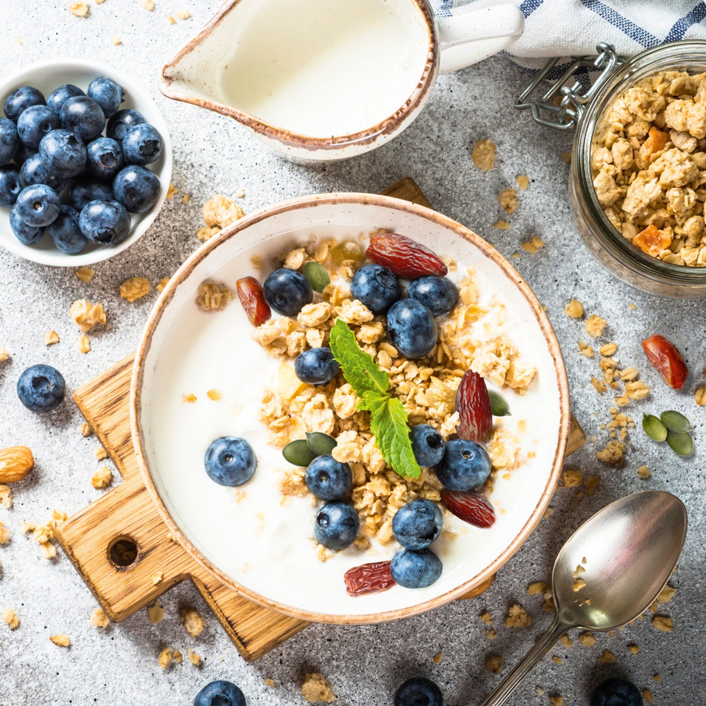 Müsli-Mix Körner Kraft - 3er Set (3x 425g) mit Datteln, Kürbiskernen, Zimt, Blaubeeren und Milch serviert.