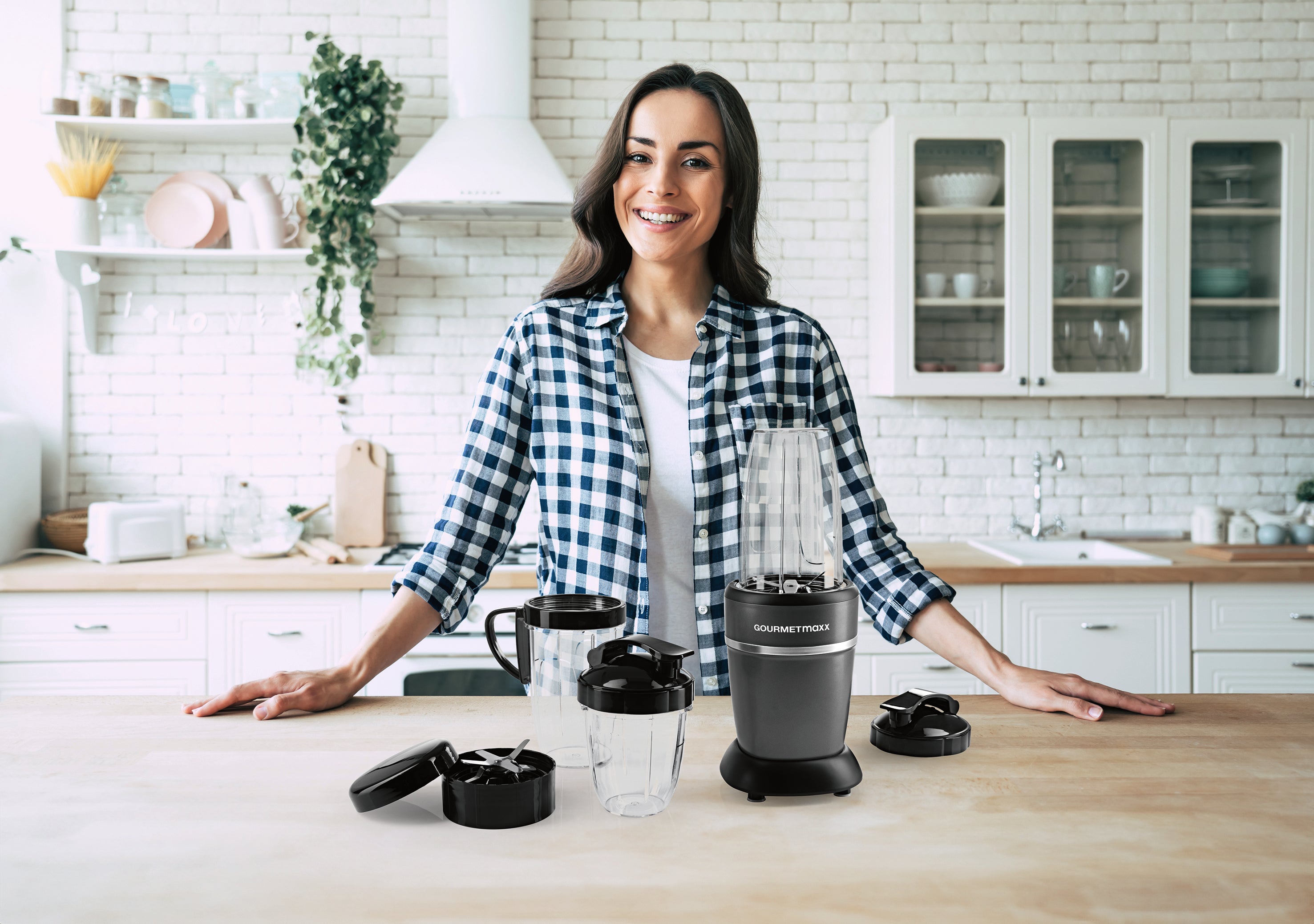 Frau in moderner Küche mit Zubehörset L für Nutrition Mixer Pro 1.000 - Schwarz, inklusive Becher und Messeraufsätzen.