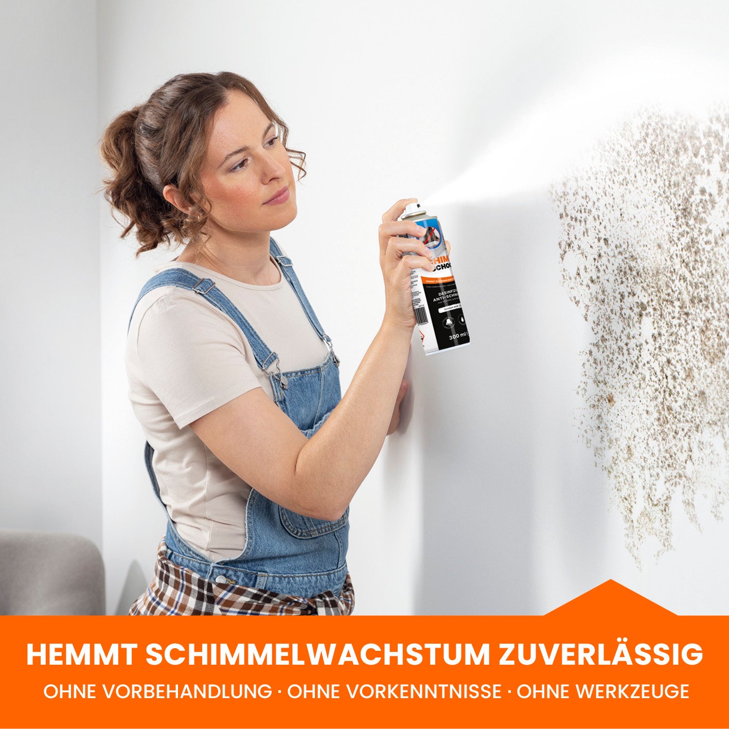 Frau sprüht Tonis SCHIMMELSCHOCK 5.1 Anti-Schimmel-Farbe Weiß auf schimmelige Wand zur zuverlässigen Schimmelbekämpfung ohne Vorbehandlung.