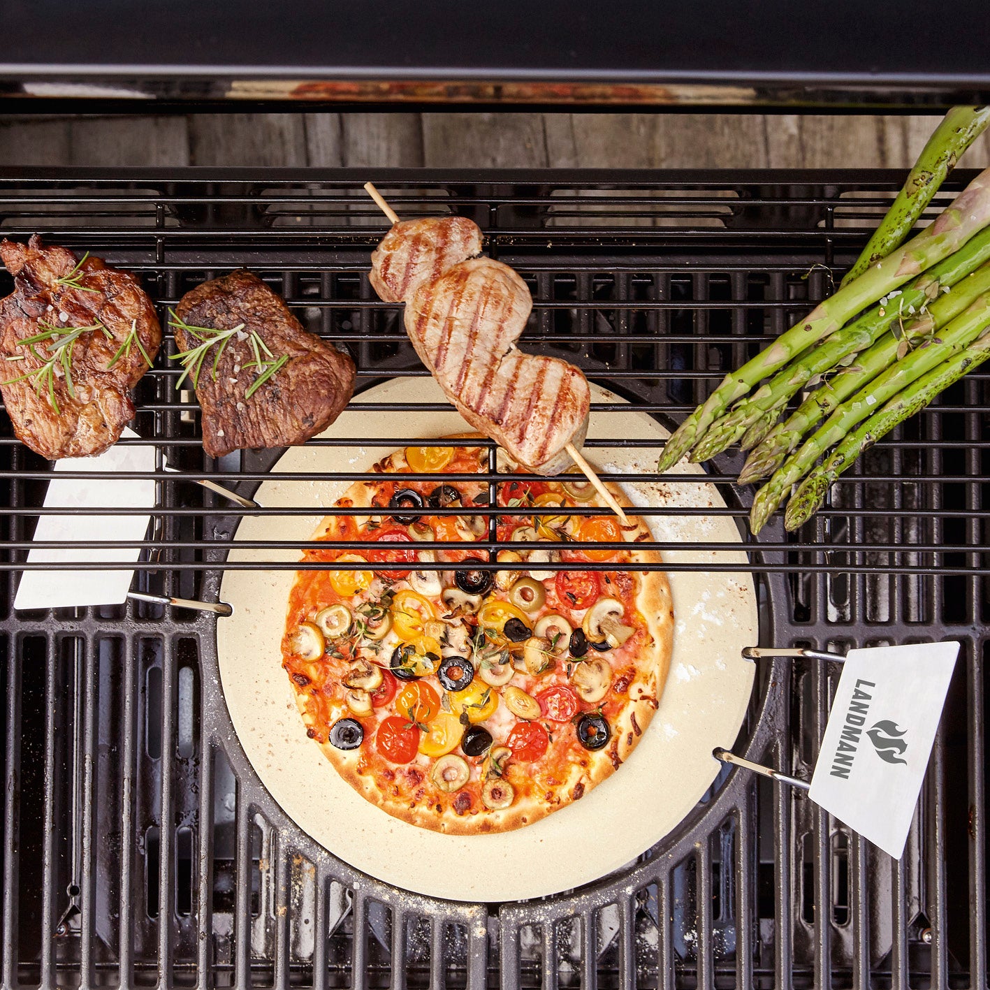 Pizzastein auf Gasgrill mit Pizza, Fleischspieß, Spargel und Steak als flexible Grillfläche aus Cordierit und Edelstahlgriffen