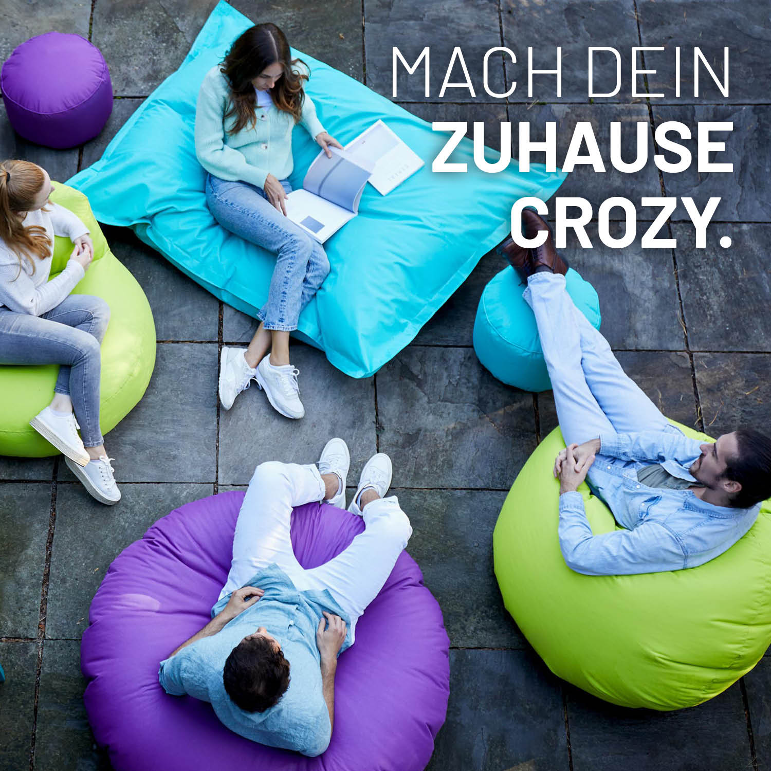 Sitzsack Drops (300 L) - indoor & outdoor - Anthrazit zeigt komfortables, modernes Sitzen und Liegen auf Terrasse mit bunten Sitzsäcken.