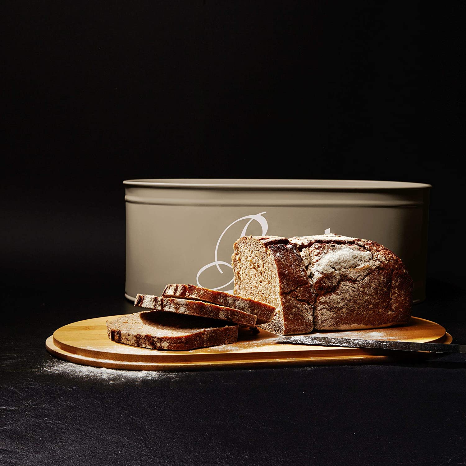 Cuisine Brotkasten aus Metall mit Bambus Deckel - Oval 36 x 20 x 13,8 cm - Grau mit geschnittenem Brot auf Bambus-Schneidebrett.