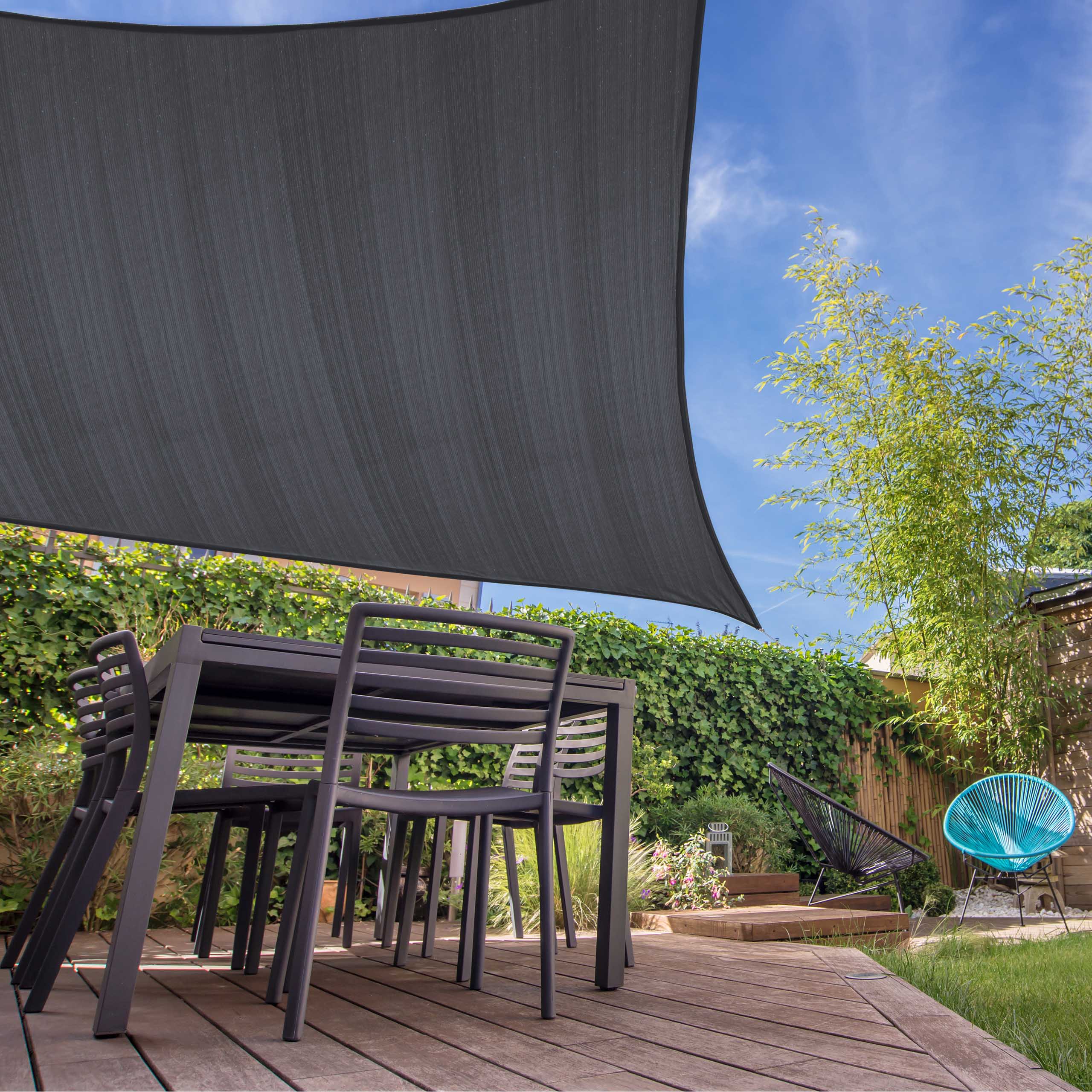 Sonnensegel 100% HDPE mit Stabilisator für UV-Schutz - Rechteck 5 x 6 Meter - Dunkelgrau über Terrasse mit Möbeln bei Sonnenschein.