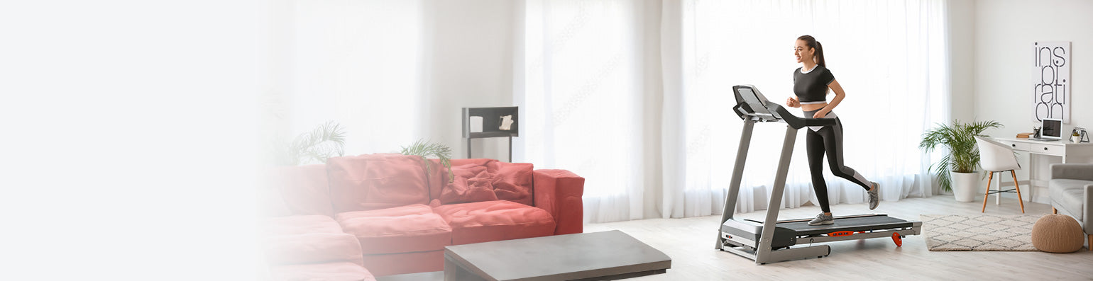 Eine Frau läuft auf einem Laufwand im Homeworkout in einem modernen Wohnzimmer mit rotem Sofa und Arbeitsplatz.