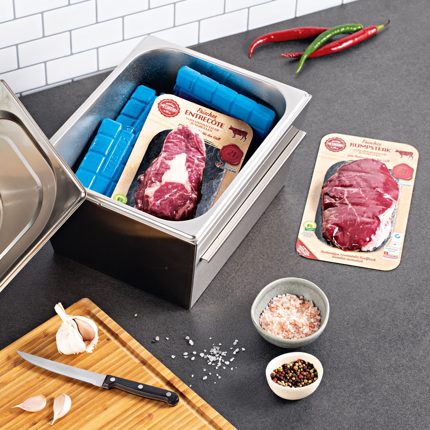 Gasgrill COOL BLACK 4.1 maxX mit Thermobox-Schublade, GN-Behälter, rohem Fleisch und Würzzutaten auf Küchenarbeitsplatte