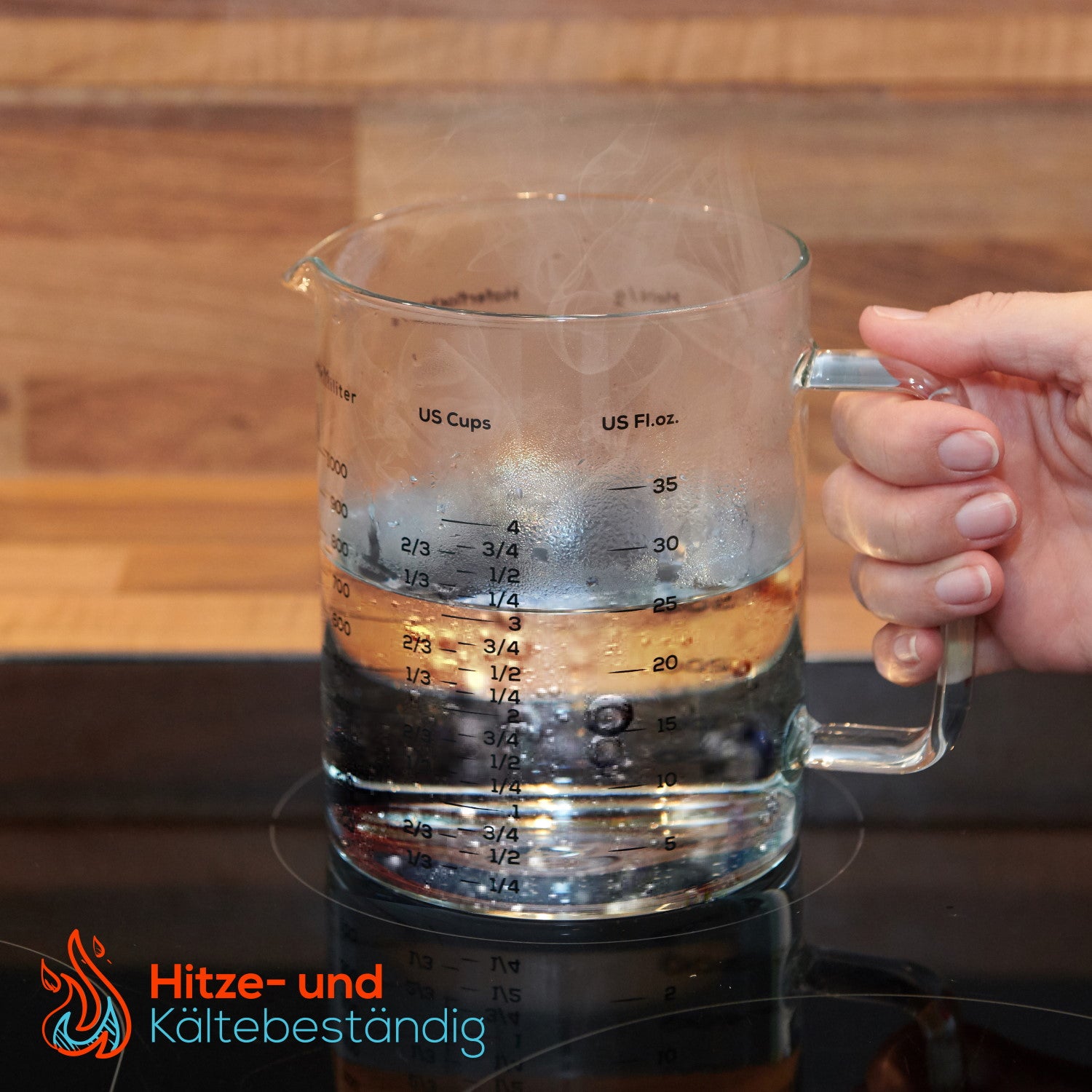Messbecher - Glas - 1 L & 500 ml - 2er Set mit hitze- und kältebeständigem Glas, gefüllt mit Wasser auf Herdplatte, Hand hält Griff