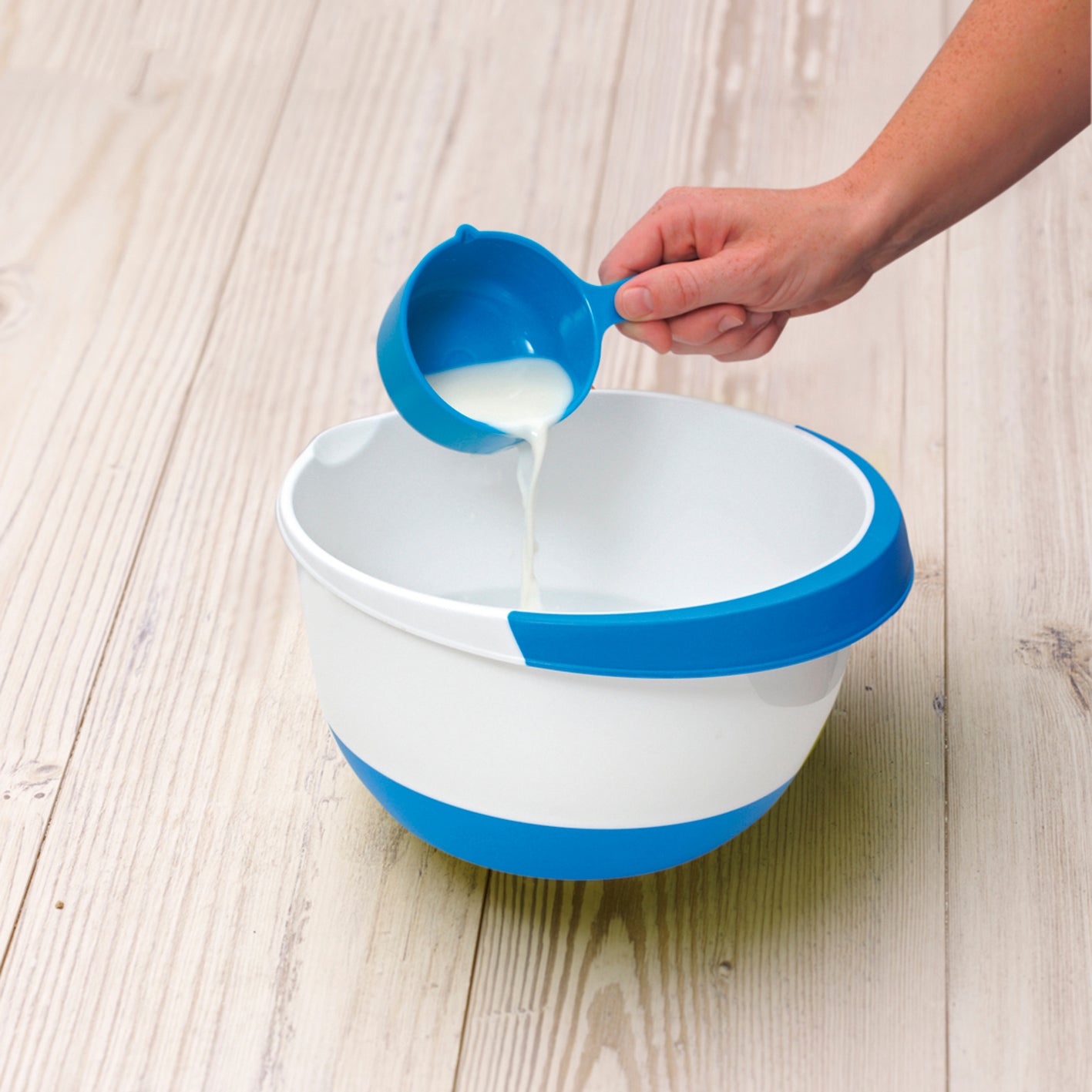 Blaues Messbecher-Set aus Rezeptbuch inkl. Messbecher-Set - Band 1 für Backprofis von morgen, Milch wird in Schüssel gegossen
