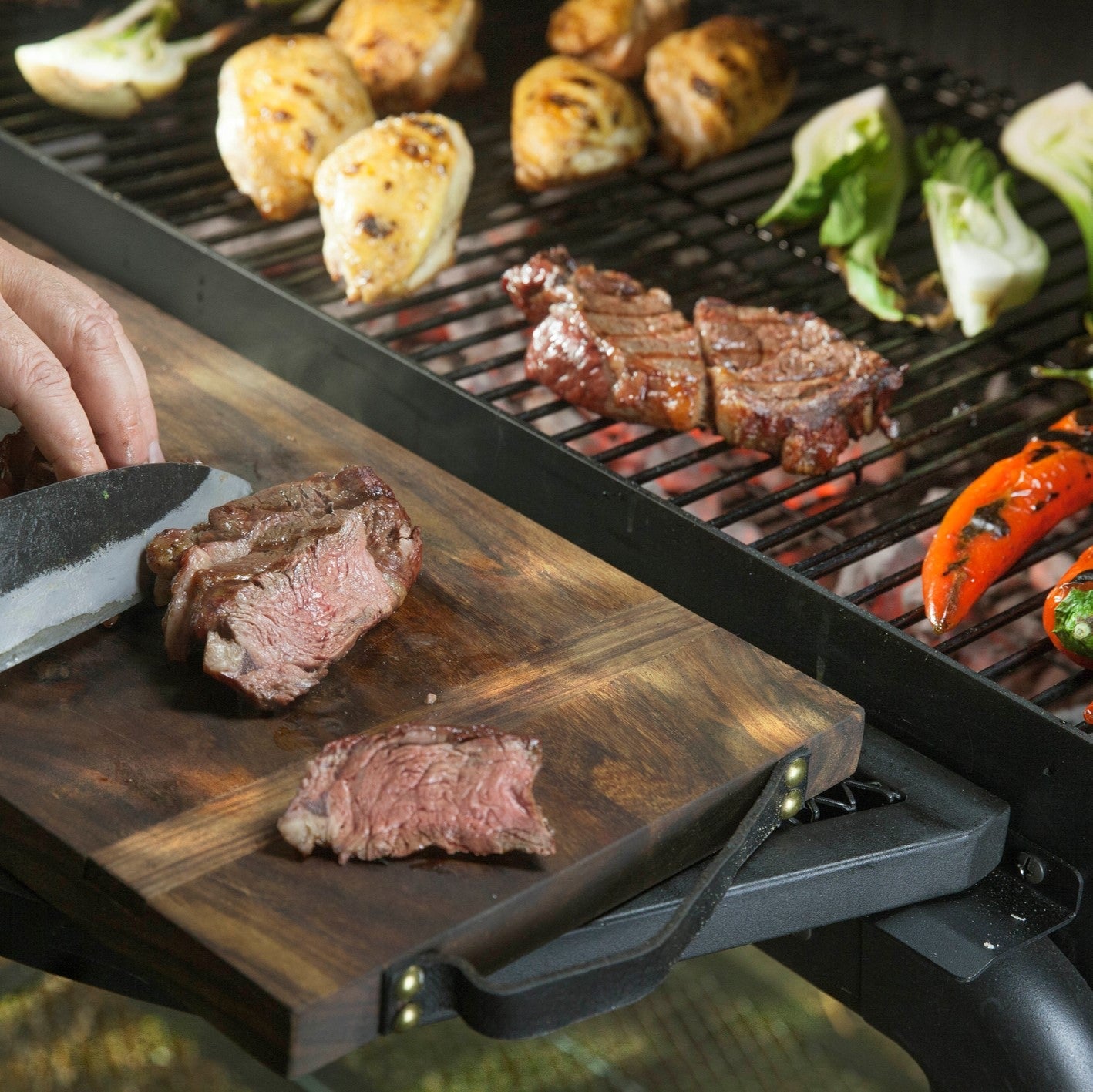 Smoker Vinson 500 mit gegrilltem Fleisch, Gemüse und Edelstahlgriffen zeigt 4-in-1 Smokerfunktion und abgerundetes Design.