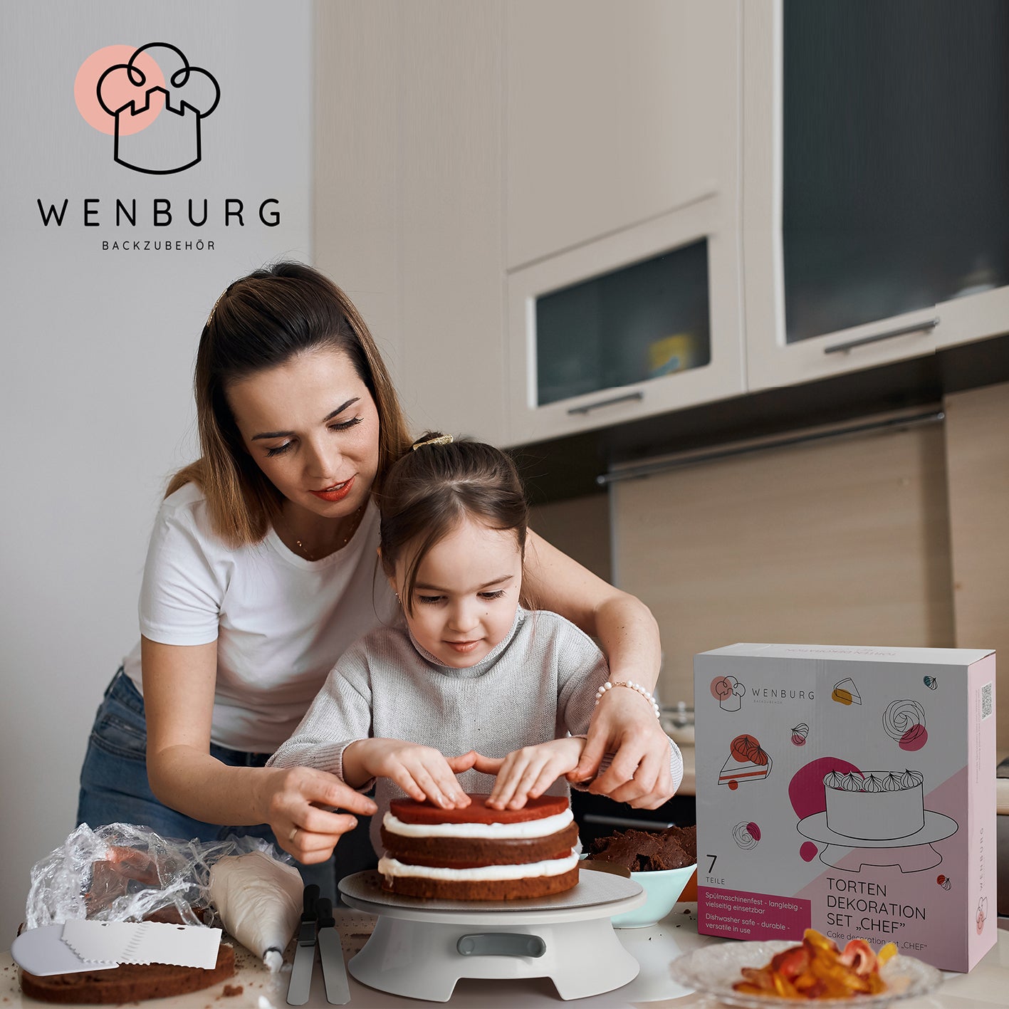 Mutter und Kind dekorieren gemeinsam Kuchen mit dem Tortendeko-Set mit drehbarer Tortenplatte von Wenburg in moderner Küche.