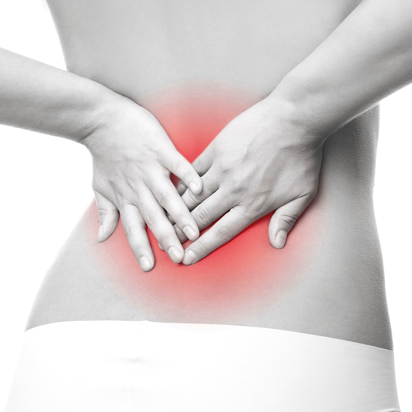 Frau hält sich den schmerzenden unteren Rückenbereich, symbolisiert Einsatz des Schmerztherapie-Gerät Ultraschall bei Schmerzen.