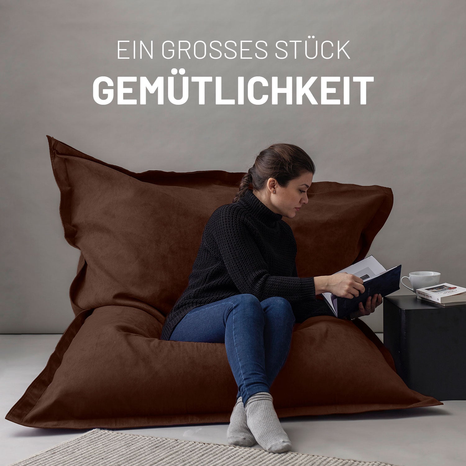 Frau sitzt auf XXL Microvelours Sitzsack (380 L) Braun von Lumaland, gemütlich und stylisch im Wohnzimmer.