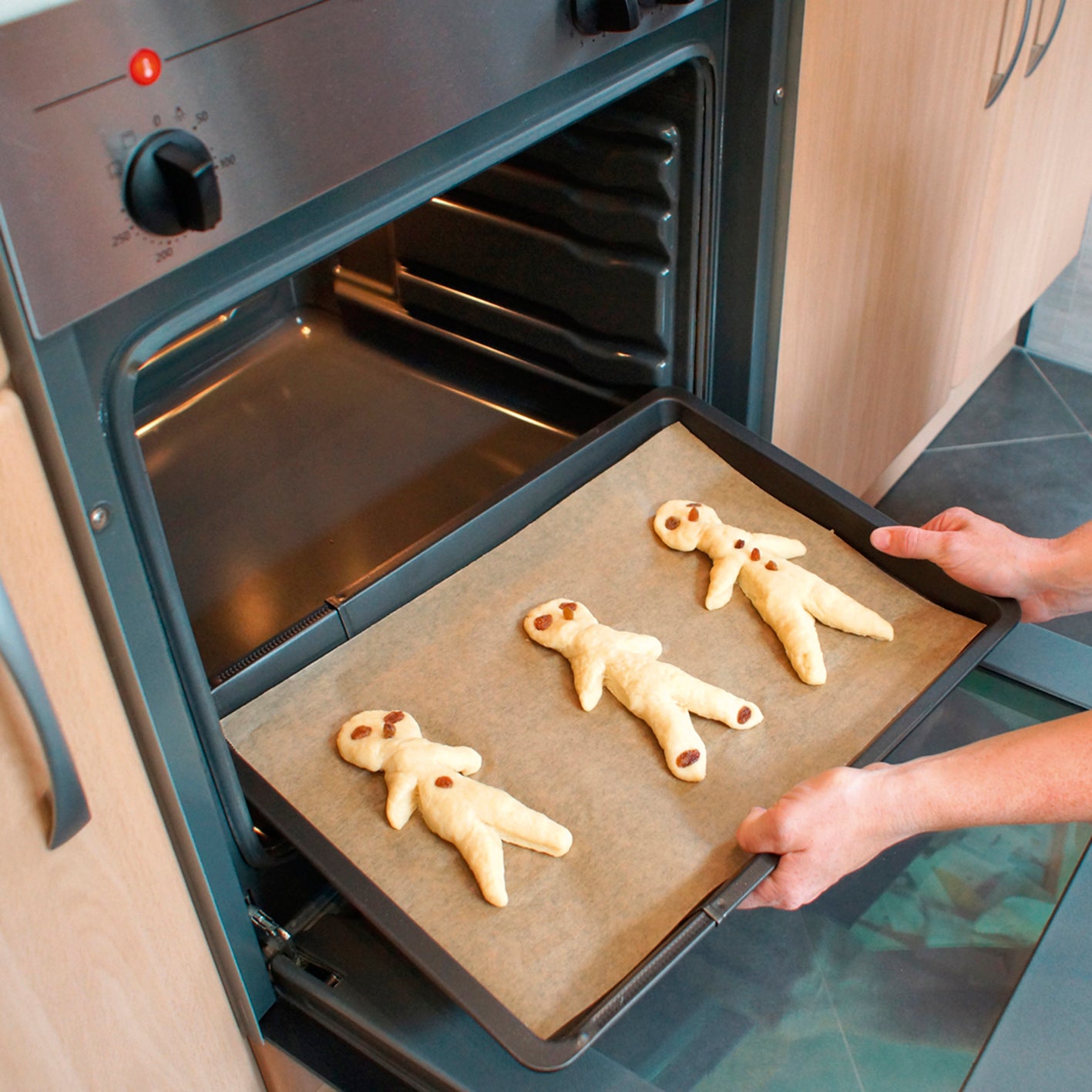 Kind legt Formen aus Teig in den Backofen, passend zum Rezeptbuch inkl. Messbecher-Set - Band 1 - Für die Backprofis von morgen (DIN-A5)