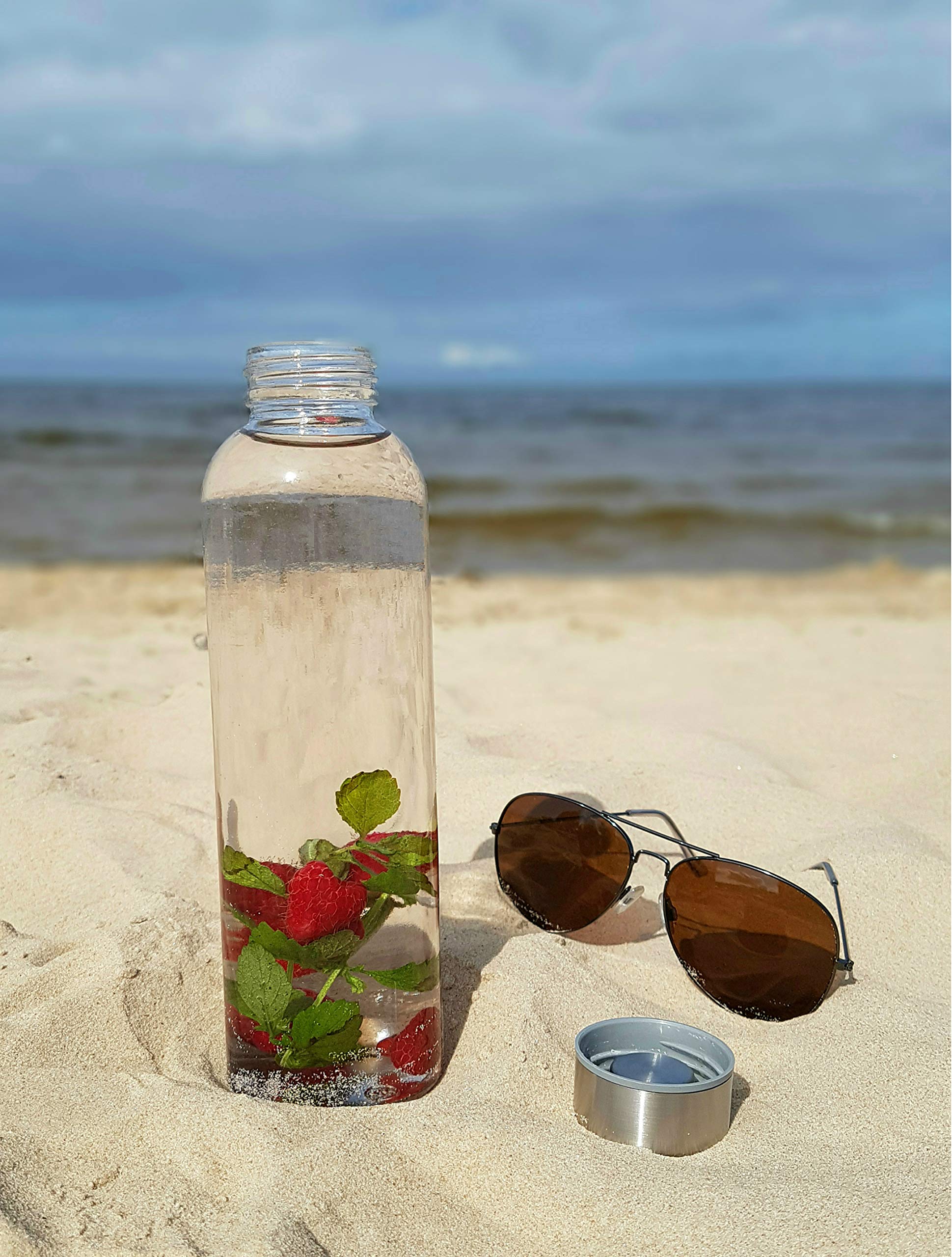 Glasflaschen-Set - 6 Stück à 500 ml, robuste und stilvolle Kalk-Natron-Glasflasche am Strand mit Früchten und abgenommenem Deckel.