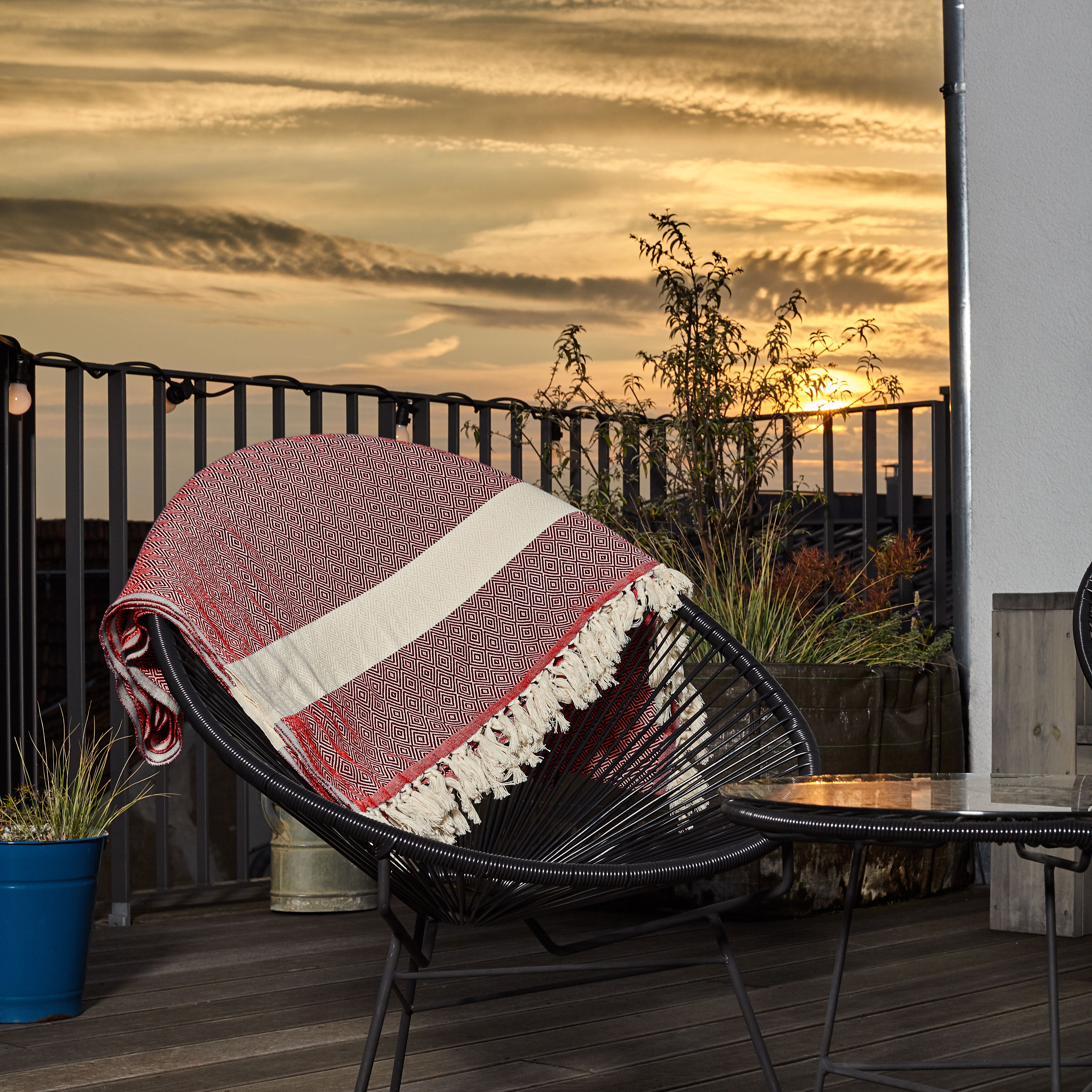 Baumwolldecke / Tagesdecke aus 100 % Baumwolle - ca. 200 x 240 cm - Rubin Rot auf Stuhl im Außenbereich bei Sonnenuntergang.